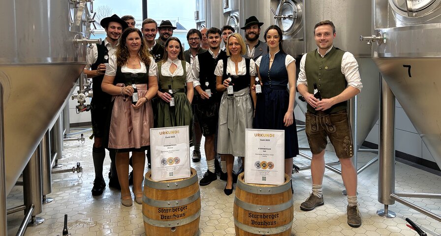 Starnberger Brauhaus Team in Trachtenkleidung, davor stehen Urkunden.