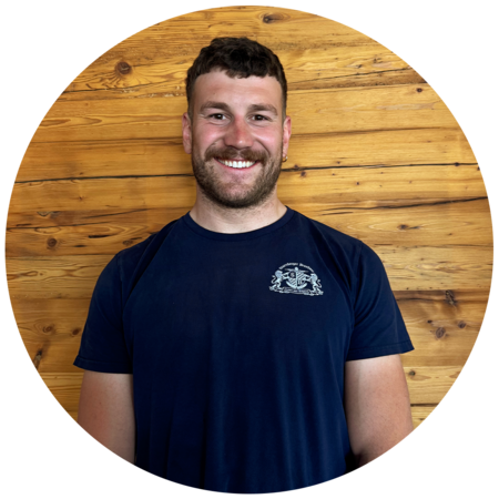 Junger Mann mit dunkelbraunen Haaren und einem Dreitagebart, trägt ein dunkelblaues T-Shirt mit dem Starnberger Brauhaus Logo.