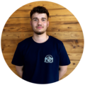 Junger Mann mit dunkelbraunen, lockigen Haaren und einem Bart, trägt ein dunkelblaues T-Shirt mit dem Starnberger Brauhaus Logo.