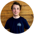Junger Mann mit brauenen, leicht gewellten Haaren, trägt ein dunkelblaues T-Shirt mit dem Starnberger Brauhaus Logo.