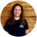 Frau mit braunen, lockigen Haaren, trägt ein dunkelblaues T-Shirt mit dem Starnberger Brauhaus Logo.
