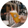 Hand füllt ein Glas mit Bier, auf dem ein Starnberger Brauhaus Logo platziert ist.